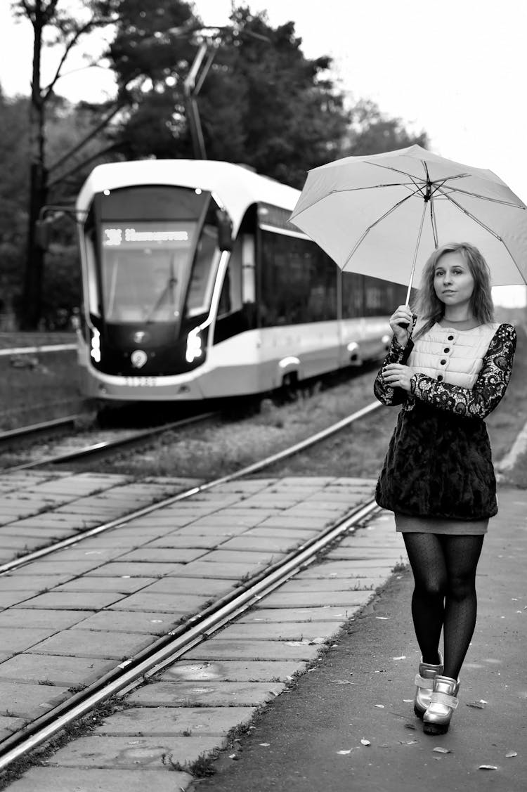 A Woman Holding An Umbrella Beside The Train