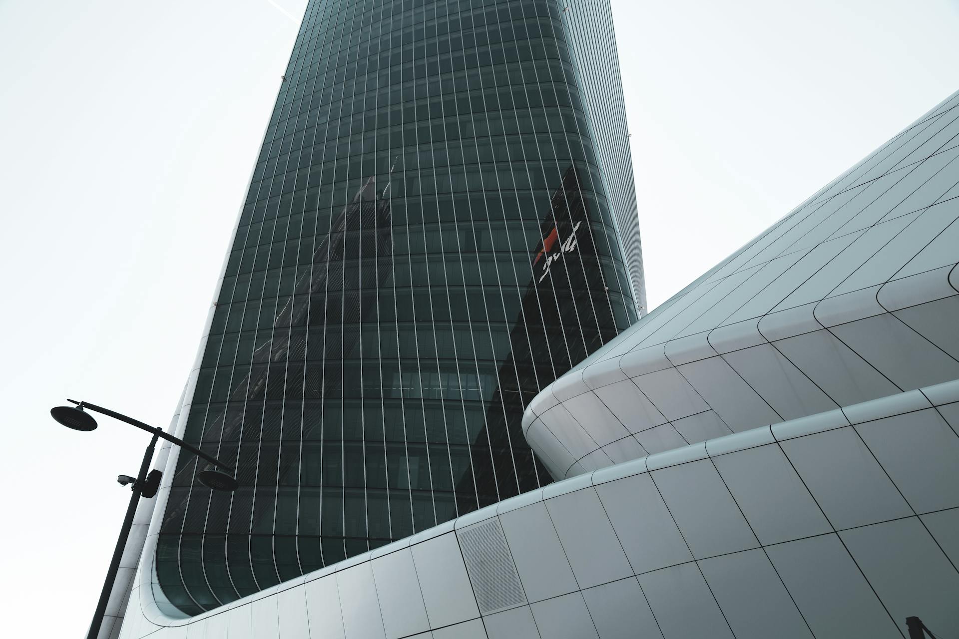 Low angle view of a glass skyscraper in Milan, emphasizing modern architectural design and urban reflection.