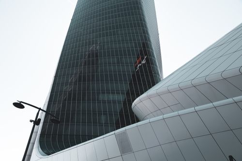 Free Low angle view of a glass skyscraper in Milan, emphasizing modern architectural design and urban reflection. Stock Photo
