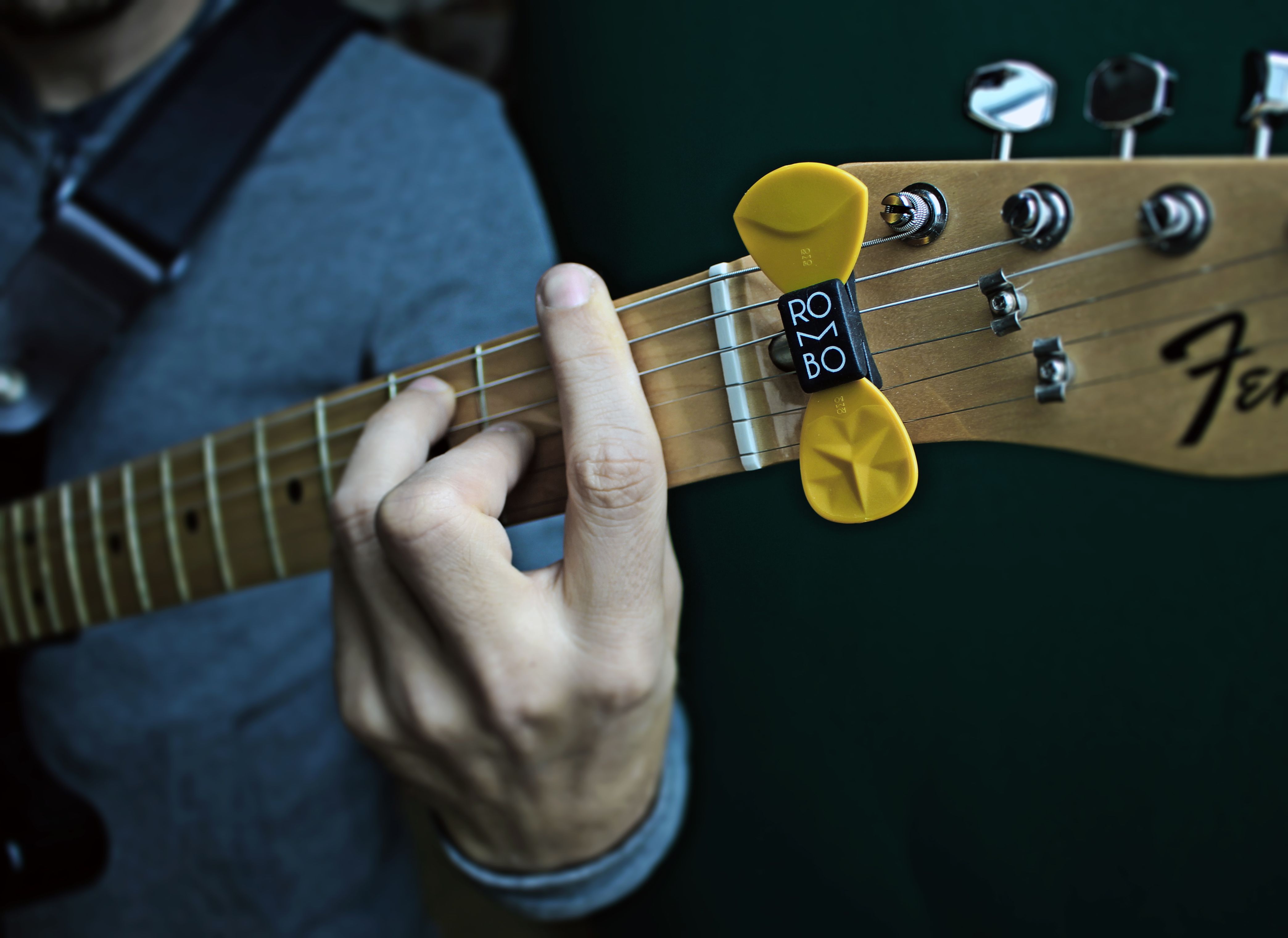 Close-up of guitarist playing an electric guitar using a yellow plectrum.