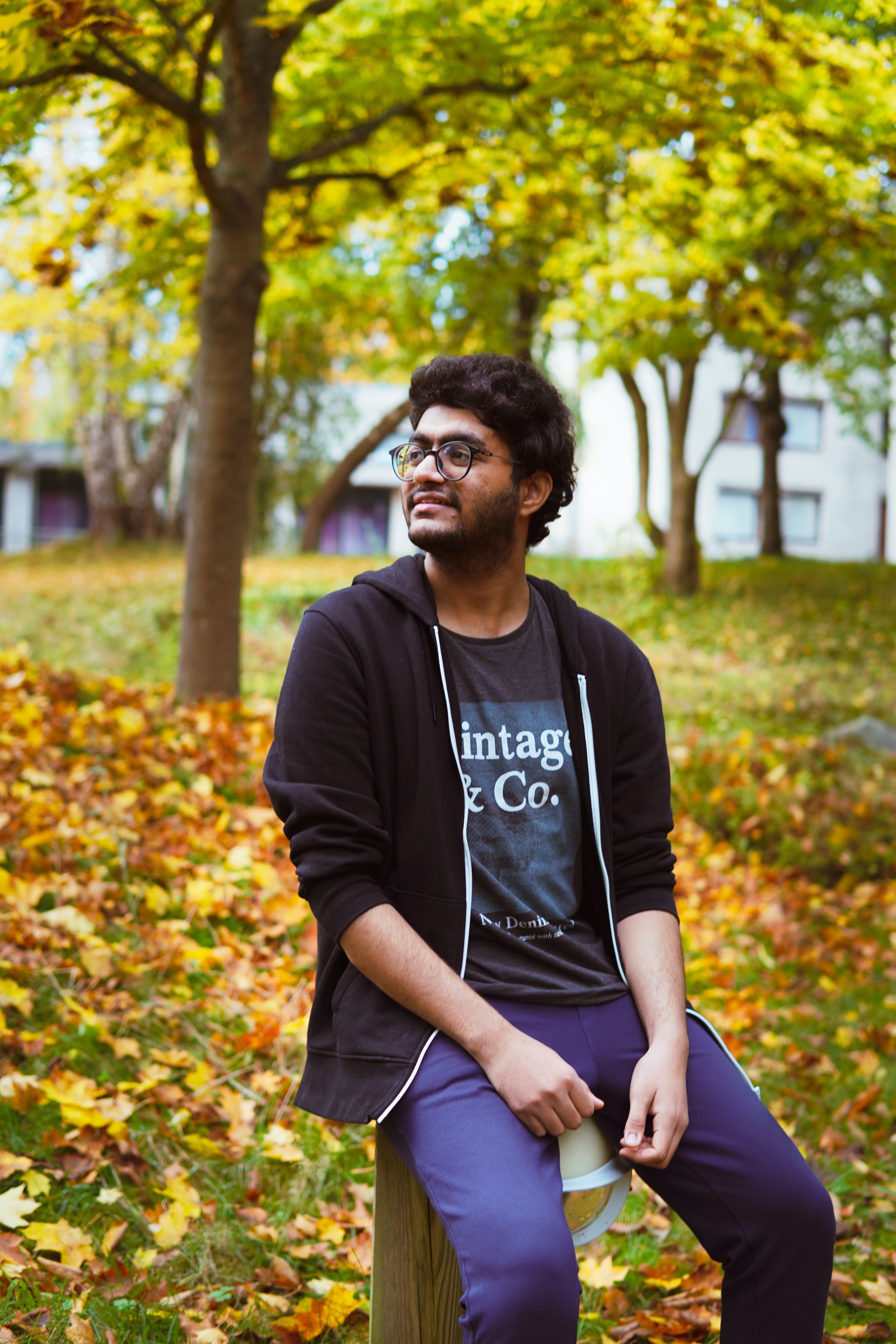 Man sitting on a bench in a park surrounded by autumn leaves, enjoying a peaceful fall day.