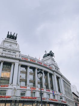 Low angle shot of historic building facade with statues under a gloomy sky.