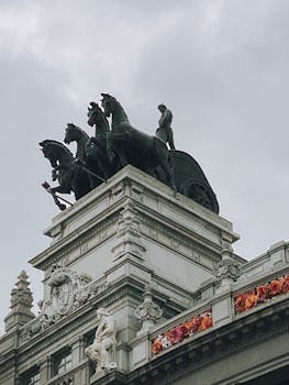 Impressive rooftop sculptures on a historic landmark under a cloudy sky.