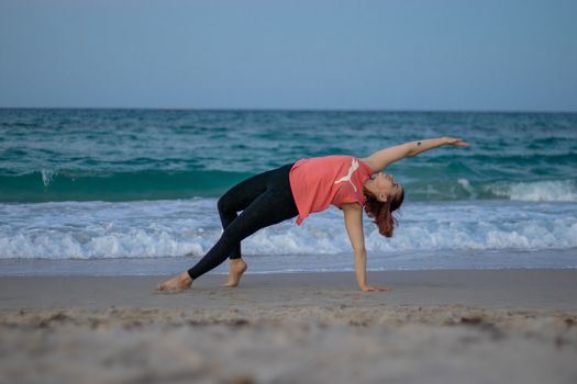 A woman performs a yoga pose on a beach in Mahdia, Tunisia, promoting fitness and healthy living.