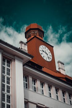 Red-brick clock tower with classic architecture against a dramatic blue sky.
