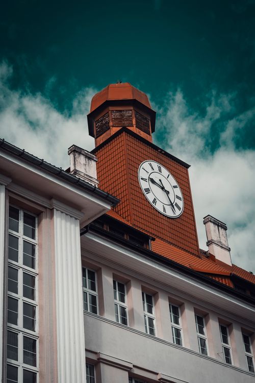 Free Red-brick clock tower with classic architecture against a dramatic blue sky. Stock Photo