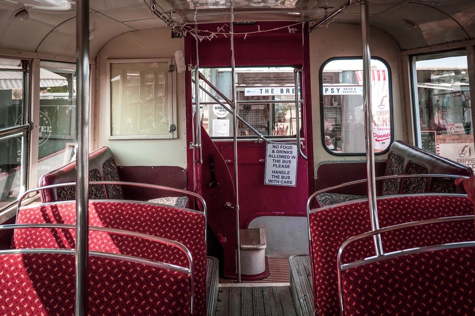Explore the classic interior of a vintage double-decker bus featuring red patterned seats and a retro ambiance.