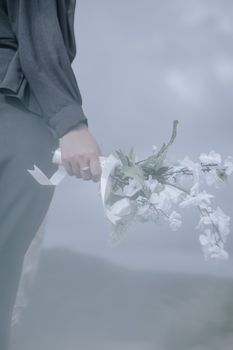 A soft-focus shot of a hand holding a delicate bouquet of white flowers, exuding elegance and calm.