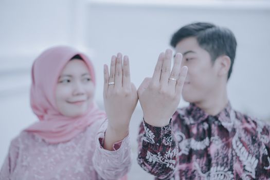 Couple in traditional attire displaying wedding rings, symbolizing their engagement. - Fotografer Sidoarjo