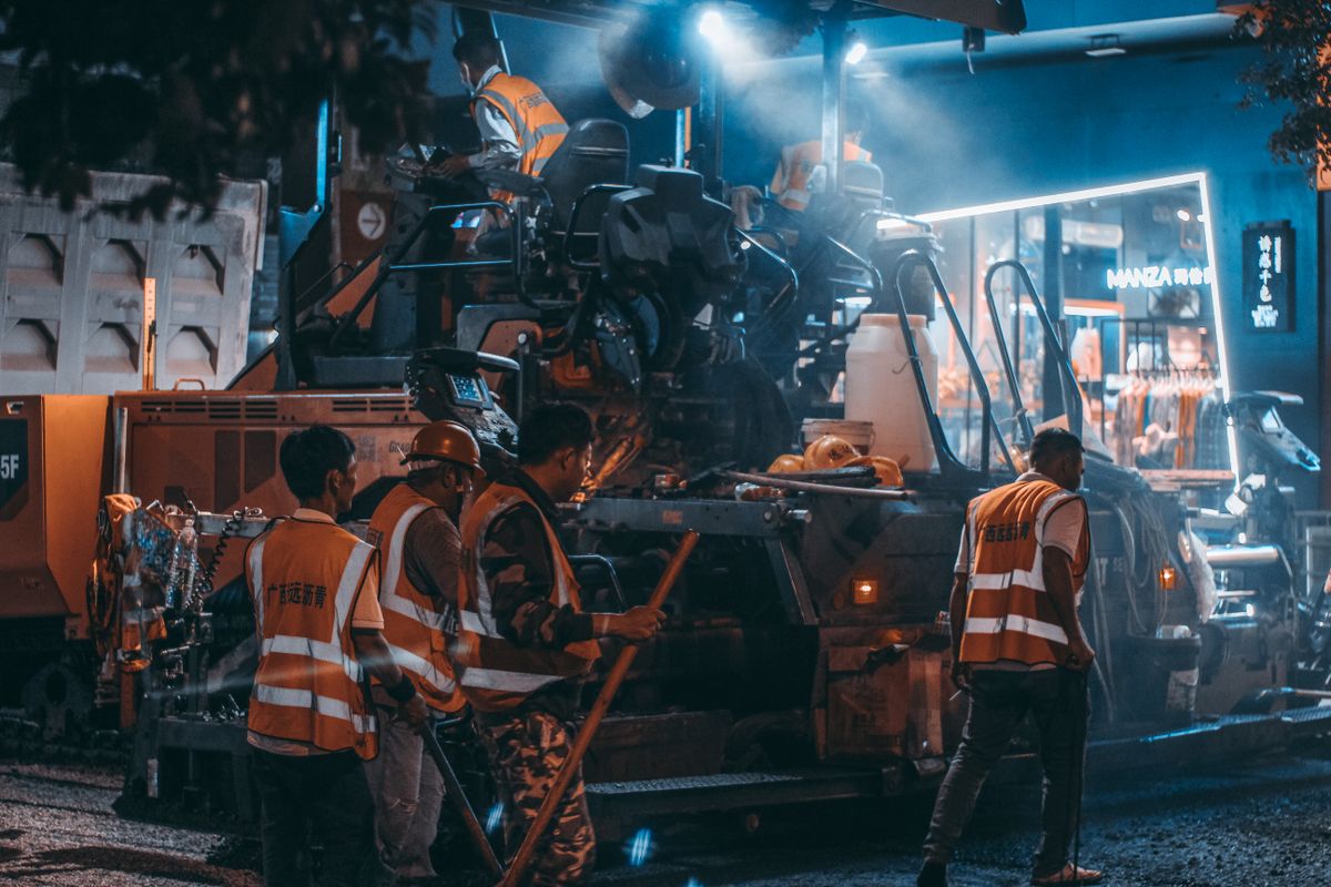 Workers operating heavy machinery during asphalt laying on a road resurfacing job