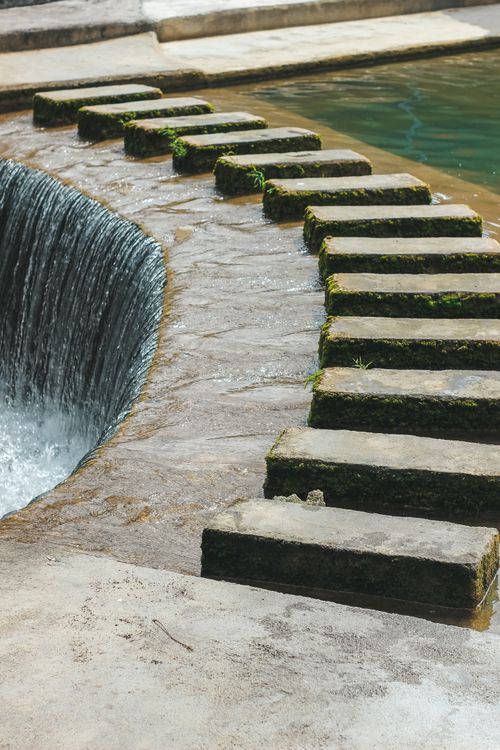 Free Elegant concrete stepping stones alongside a flowing water feature in a modern architectural setting. Stock Photo
