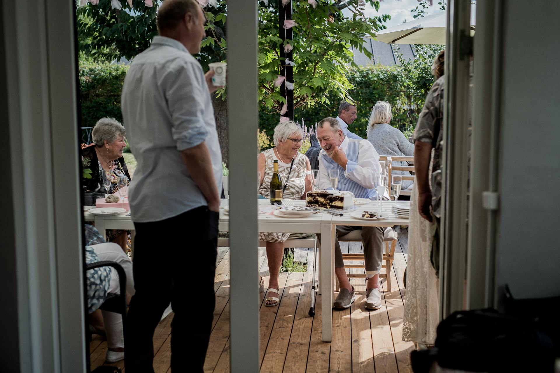 A relaxed outdoor gathering with friends enjoying food and drinks in a garden setting.