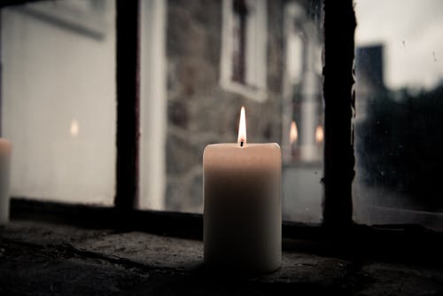 Pillar Candle Near Clear Glass Window