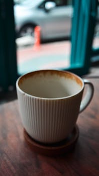 Empty coffee cup on a table with subtle cafe background blur.