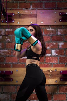 A woman in active wear boxing indoors, showcasing strength and focus.