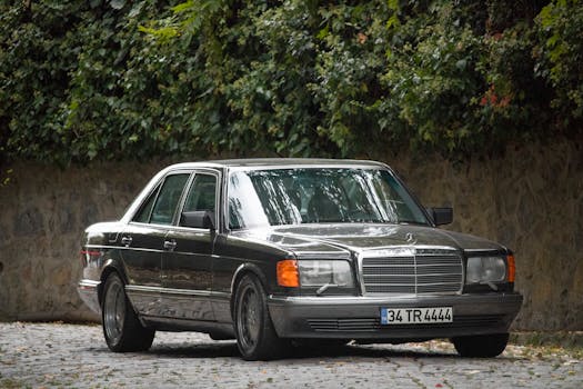 Vintage Mercedes Benz car parked outdoors against lush greenery in daylight.