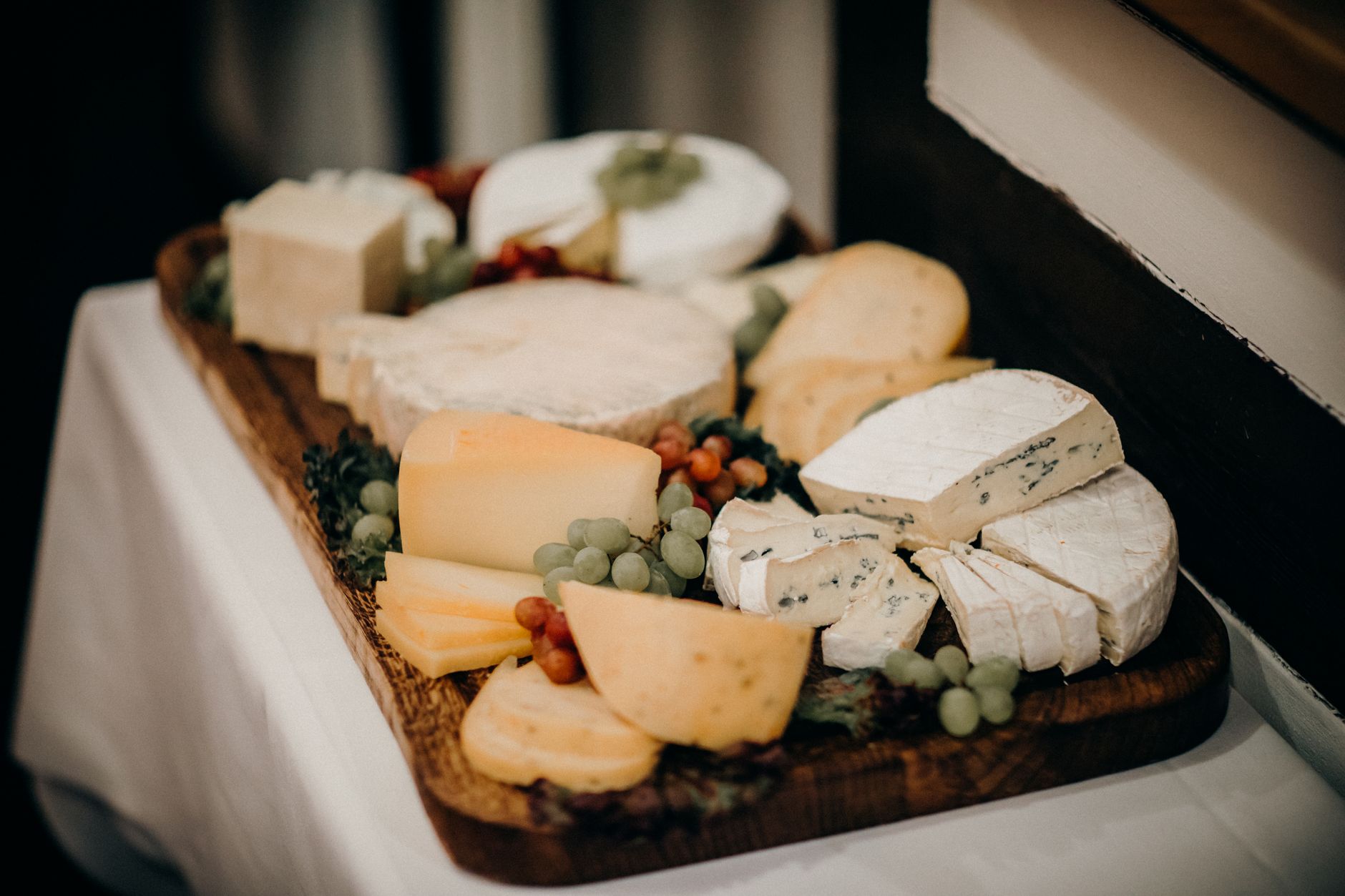 A delicious assortment of gourmet cheeses and grapes on a wooden platter.