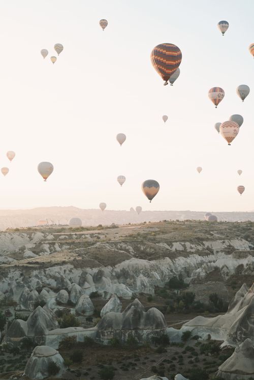 Free A breathtaking view of hot air balloons drifting over Cappadocia's unique landscapes at sunrise. Stock Photo