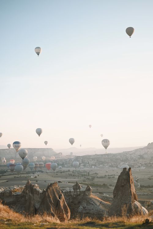 Free Hot air balloons float over Cappadocia's unique landscape at sunrise, offering a breathtaking aerial view. Stock Photo