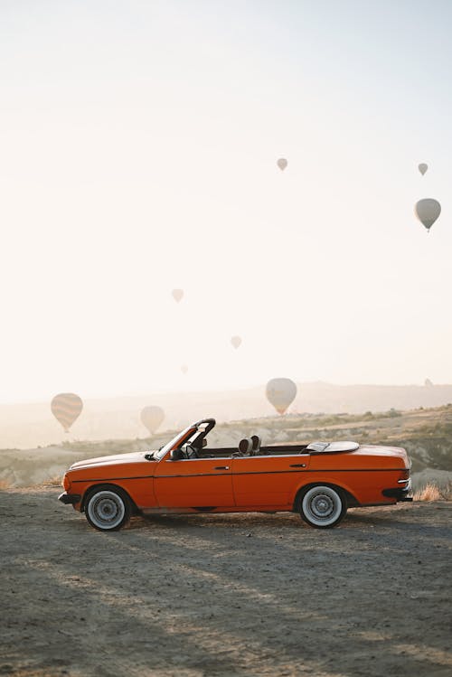 Vintage Car in Landscape with Hot Air Balloons