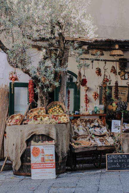 Charming village market stall with baskets of fruits and vegetables under a tree.