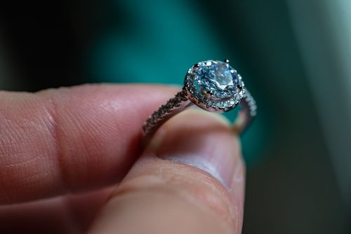 Free Close-up view of a sparkling diamond engagement ring held between fingers. Stock Photo