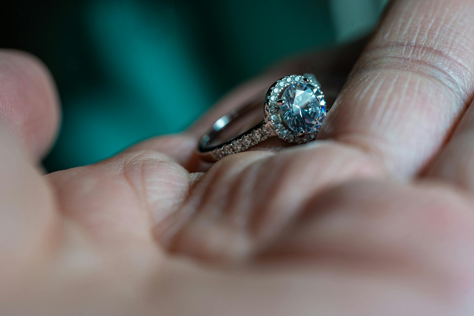 Close-up of a platinum engagement ring with diamonds on a human hand, exuding luxury and elegance.