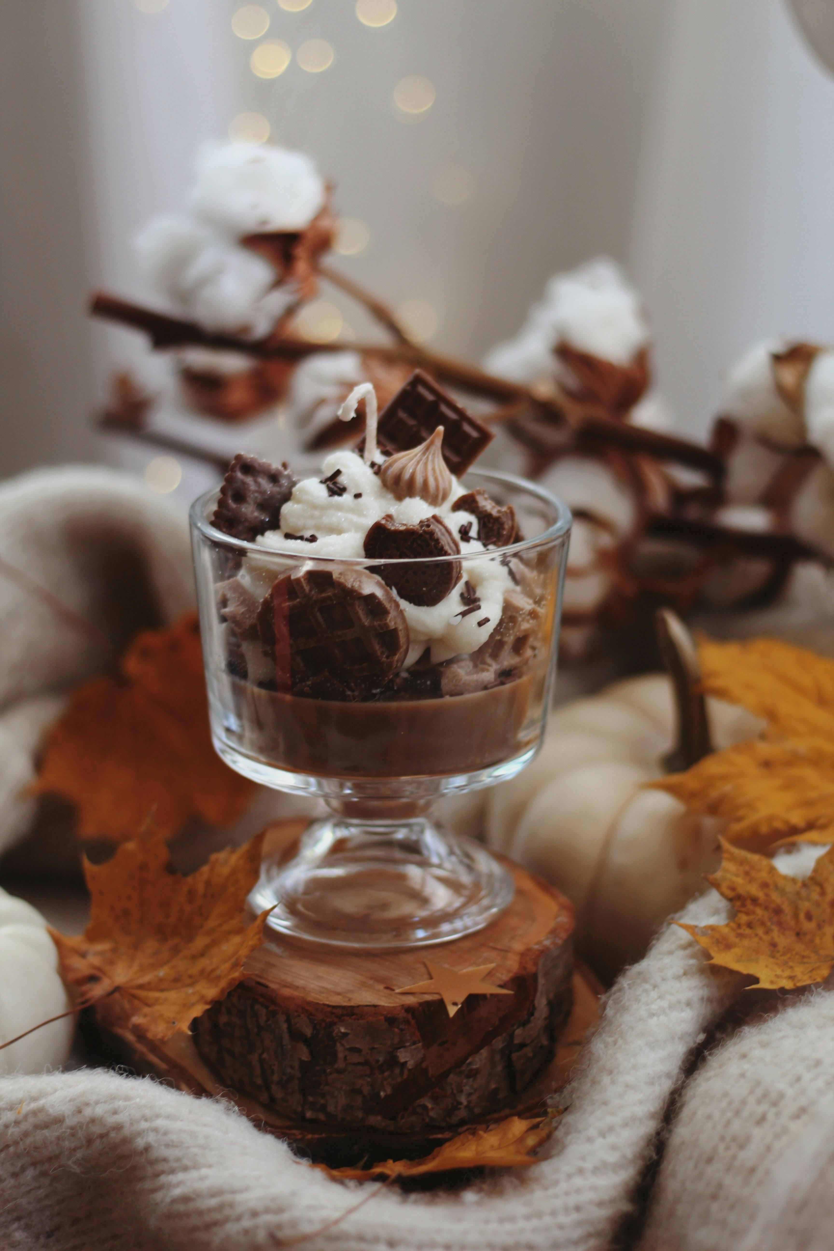 Delicious chocolate pudding dessert in a glass cup surrounded by autumn leaves.