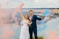 在湖边举行的户外婚礼上，幸福的夫妇举着五颜六色的烟棒