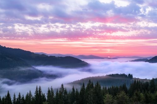 Free Breathtaking view of a pink sunrise over a mist-covered mountain landscape with clouds. Stock Photo