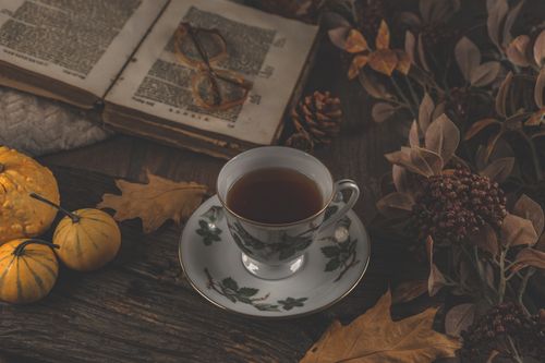 Free A warm fall scene with tea, an open book, pumpkins, and dried leaves. Stock Photo