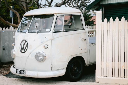 White Volkswagen Vehicle on Parking Lot Near White Wooden Picket Fence