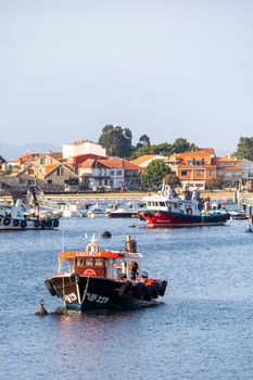 Colorful fishing boats docked in the scenic Meloxo harbor, Galicia, Spain.