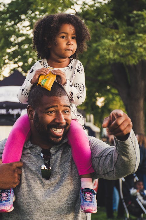 Free Man Carrying his Daughter on his Shoulders Stock Photo