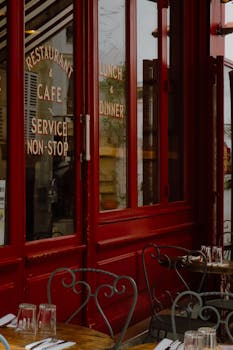 A quaint Parisian café with red doors and outdoor seating, epitomizing cozy city dining.