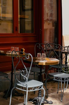 Cozy Parisian café setting with metal chairs and wooden tables under the sunlight.