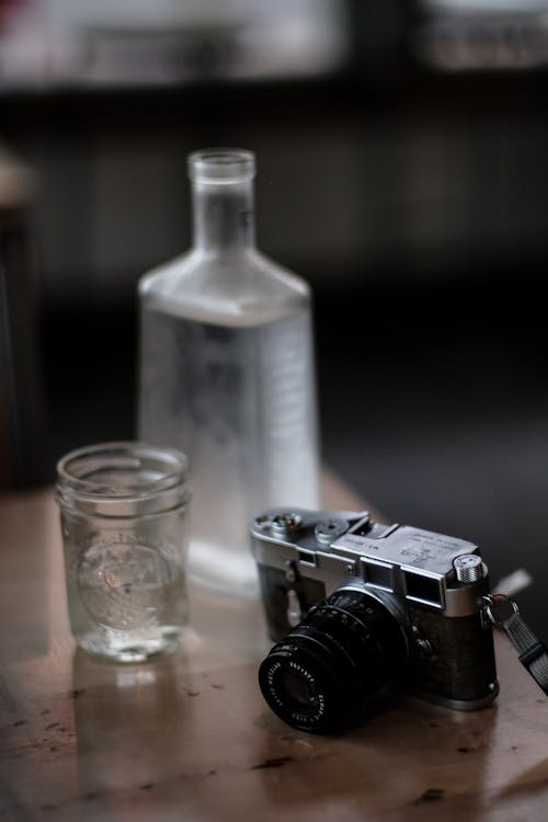 Black and Gray Camera Beside Drinking Glass