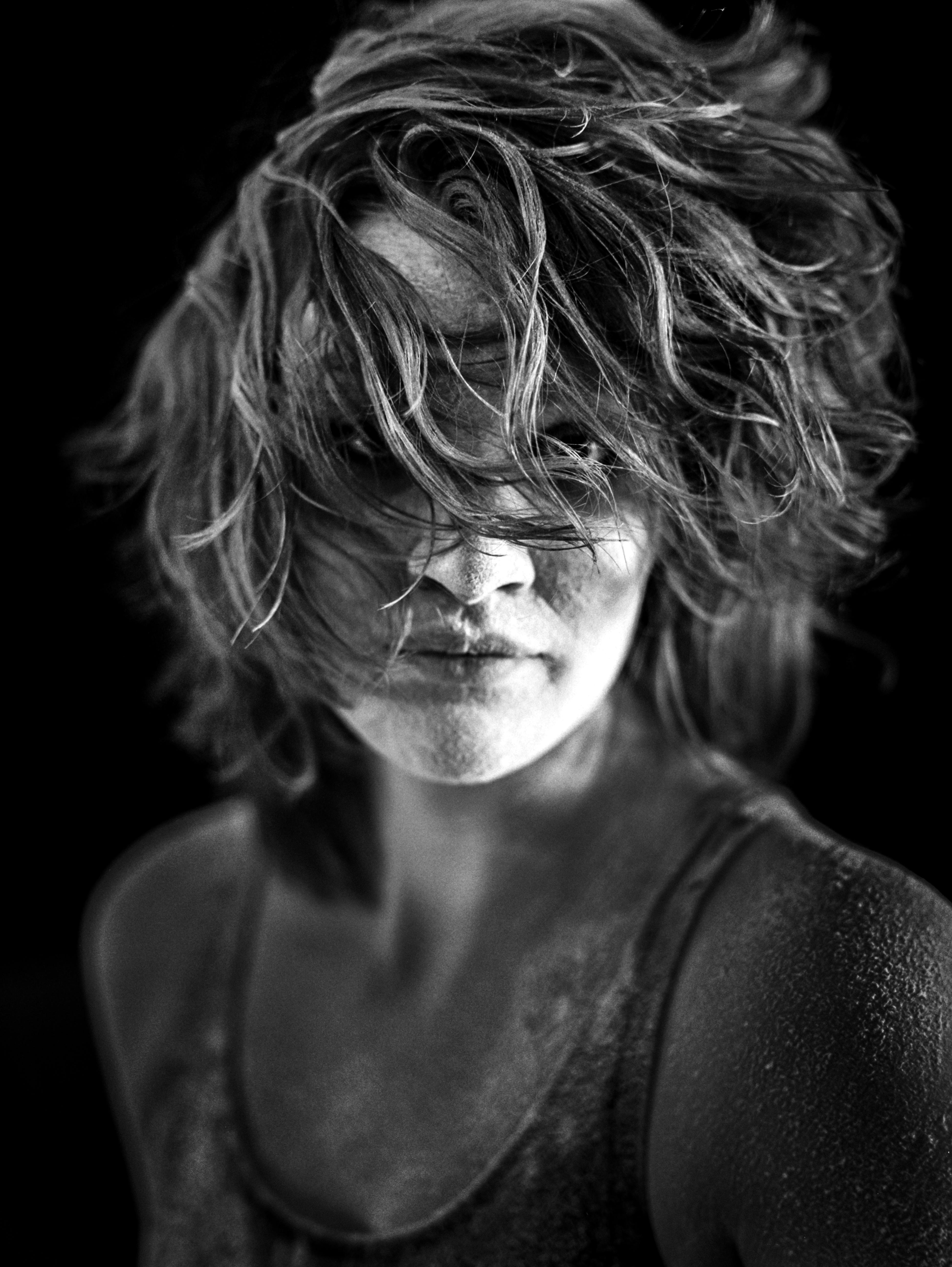 喜怒无常的黑白肖像捕捉了一位年轻女子，她有着动态的头发和富有表现力的目光