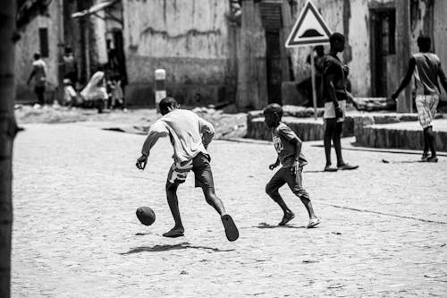 Grayscale Photo of Kids Playing Football