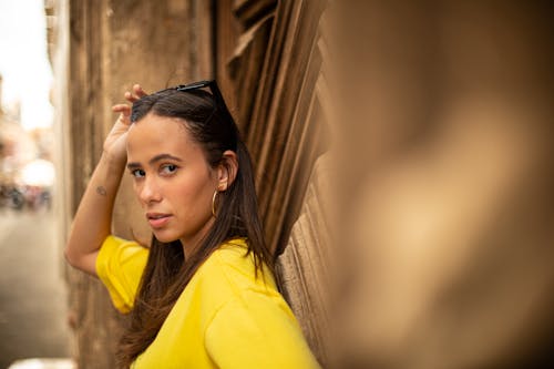 Pretty Woman in Yellow Shirt with Hand on Hair
