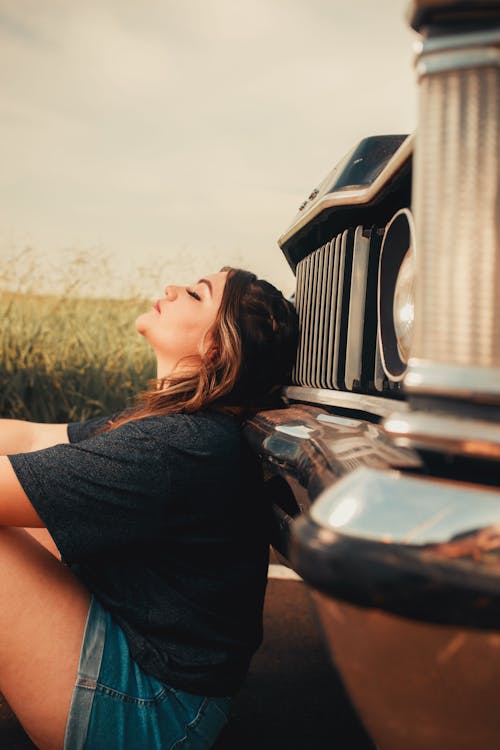 A Woman Sitting on the Floor While Leaning on the Car 