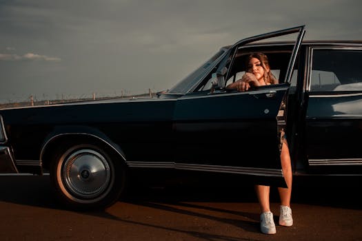 A young woman leans out of a classic car at sunset, embodying vintage style and adventure.