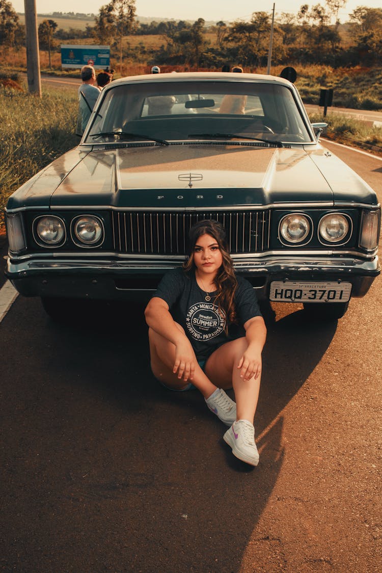 Woman Sitting In Front Of A Black Vintage Car