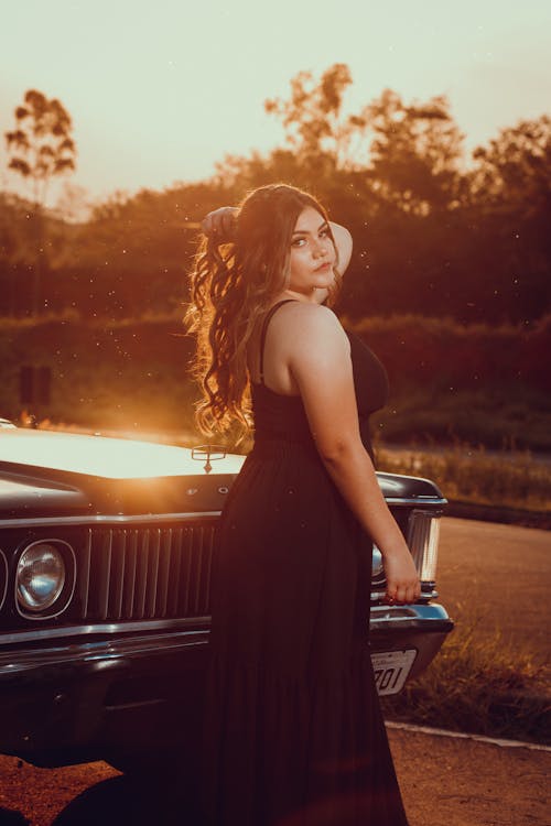 Woman in Black Spaghetti Strap Dress Standing Beside a Car