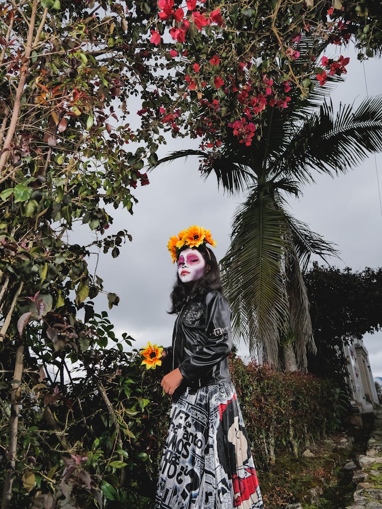 Wide Angle Shot Of A Girl With Death Painted Mask Standing In A Garden