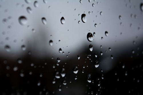 Free Abstract close-up of water droplets on glass against an overcast sky, offering a moody, introspective feel. Stock Photo
