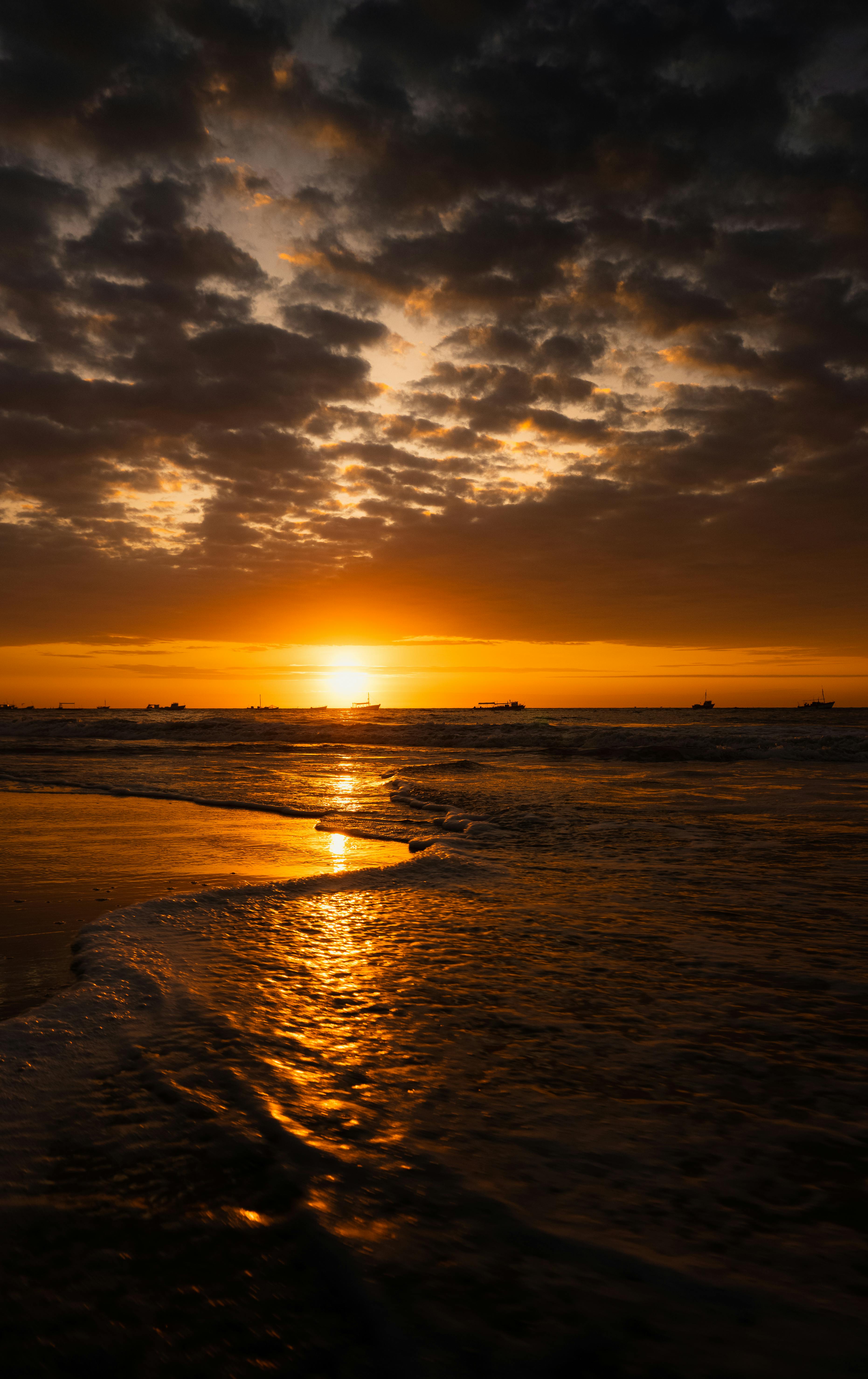 Experience the breathtaking sunset over Tumbes Beach, Peru, with golden hues reflected in tranquil ocean waves.