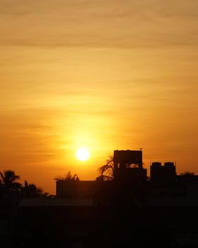 A serene sunrise over Kolkata's skyline, highlighting silhouettes against a golden sky.