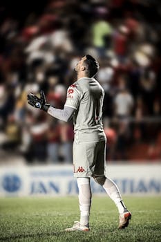 Soccer goalie in uniform, looking upward with blurred crowd background. Captured outdoors in Paraguay.