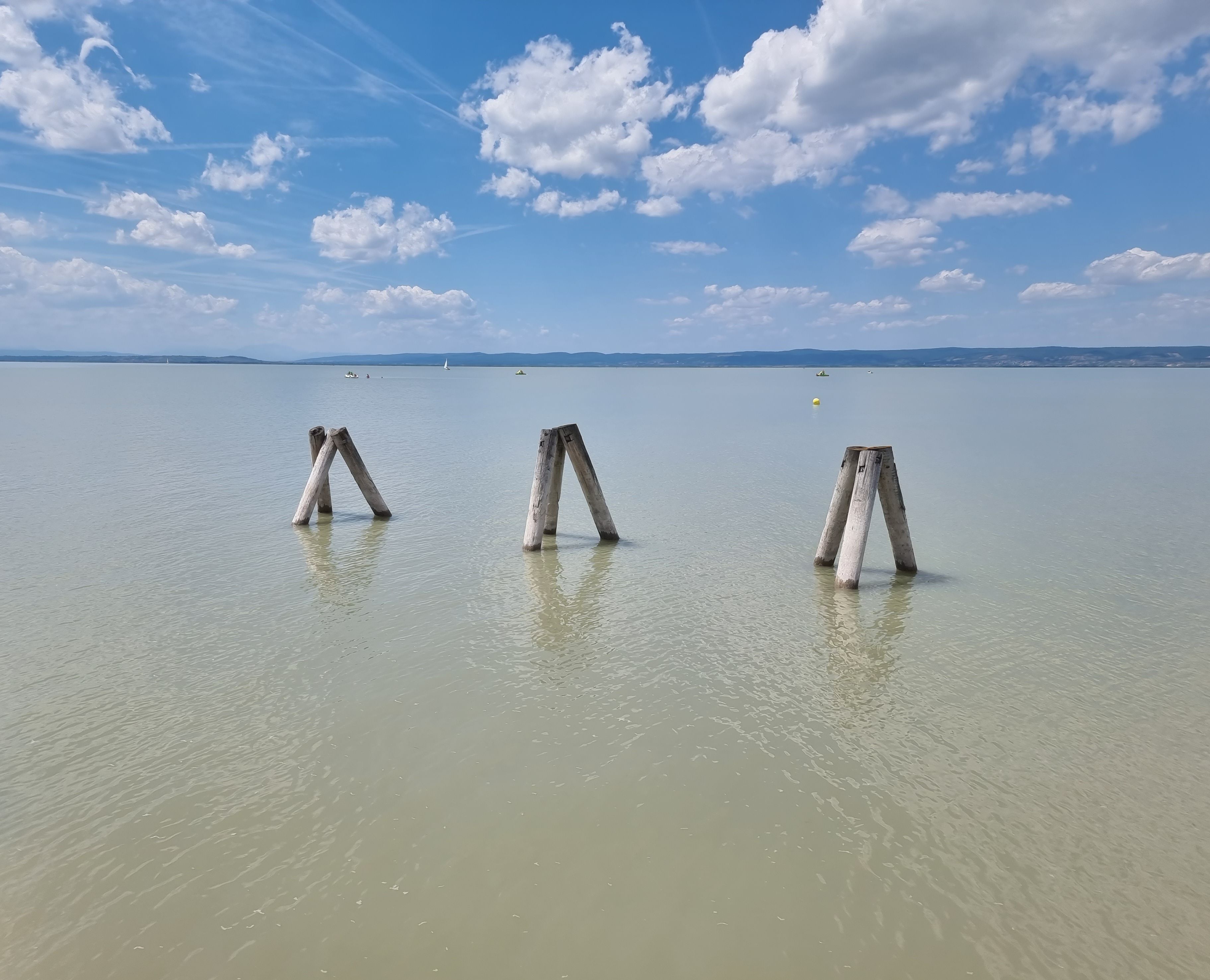 Peaceful scene of Lake Neusiedl with wooden posts and blue sky in Austria.